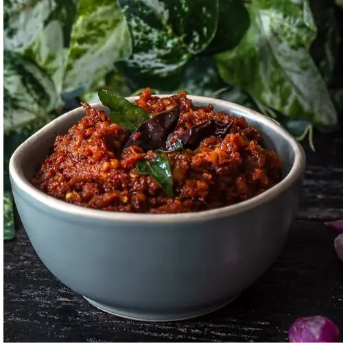 Close-up of thick kara chutney with visible red chili flakes and onion texture